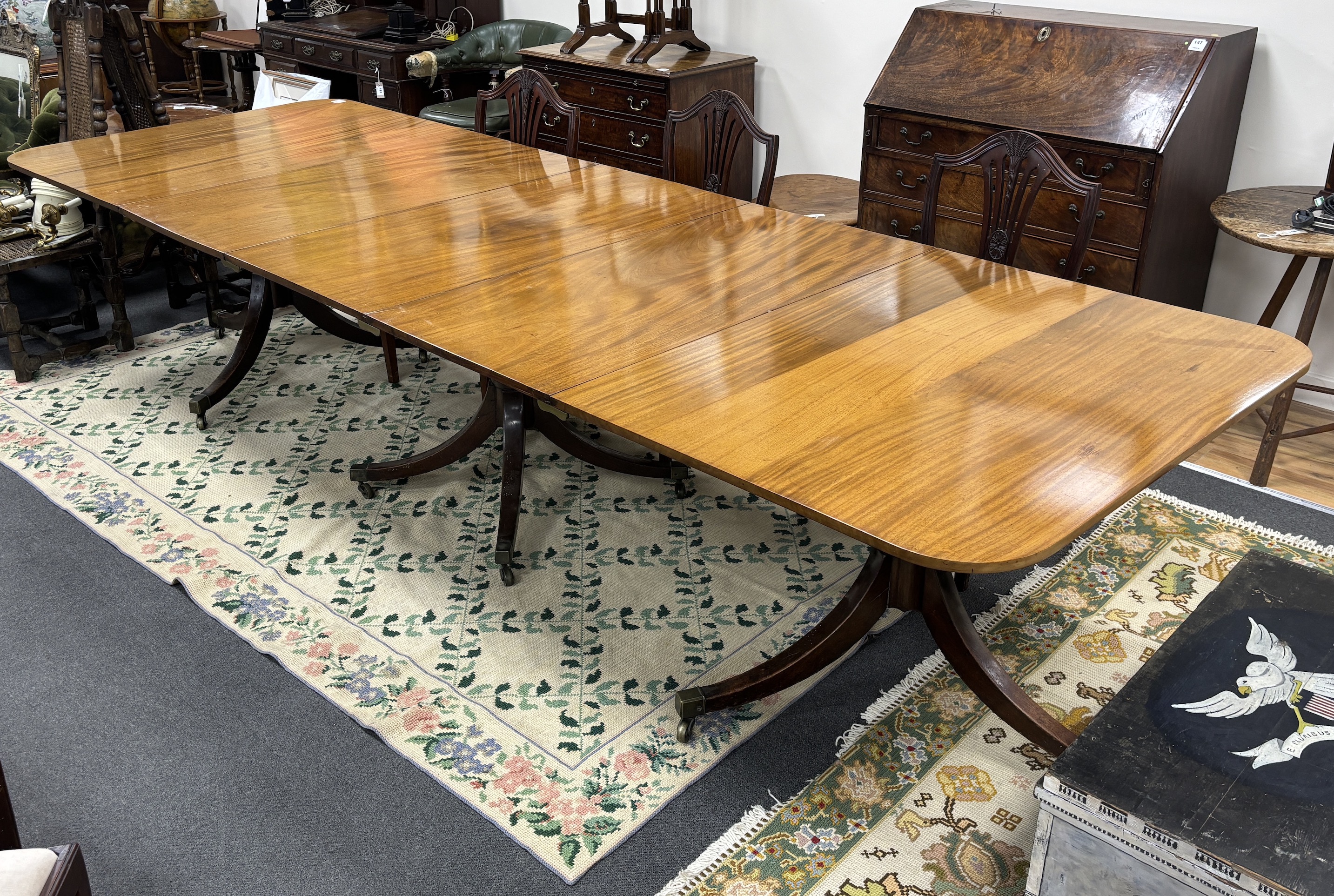 A George III style mahogany triple pillar extending dining table, 346cm extended, two spare leaves, depth 118cm, height 75cm